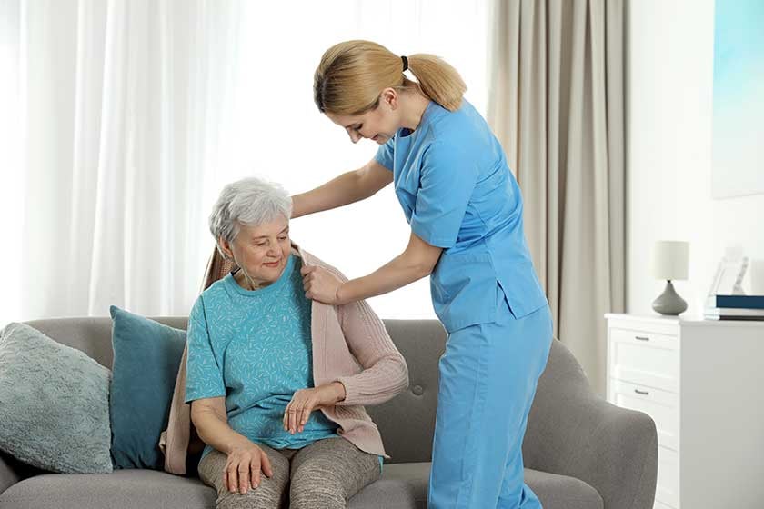 nurse-covering-elderly-woman-with-blanket-indoors-assisting-senior-people