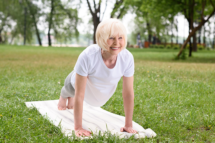 Smiling elderly woman doing plank