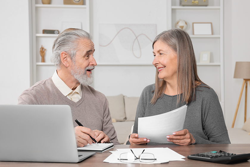 Elderly couple with papers and laptop discussing pension plan