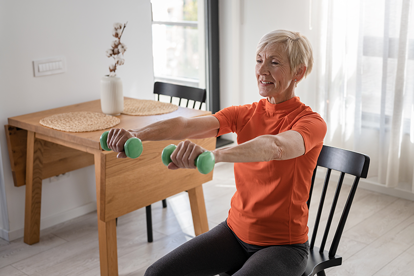 smiling-beautiful-senior-woman-health-instructor-doing-chair-exercises