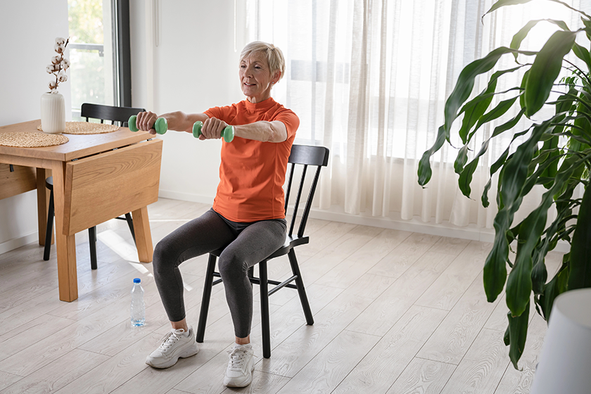 Smiling beautiful senior woman health instructor doing chair exercise